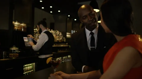 4K Bartender taking payment for drinks from smartly dressed man 库存影片 64911848