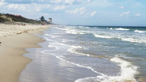 4K Beach Front Waves Crashing In Tall Hotel In Distance Video stock 104458319