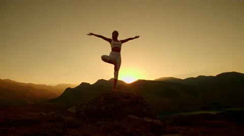 4K beautiful girl in white clothes doing yoga in the mountains,sunrise,sun flare Stock Footage