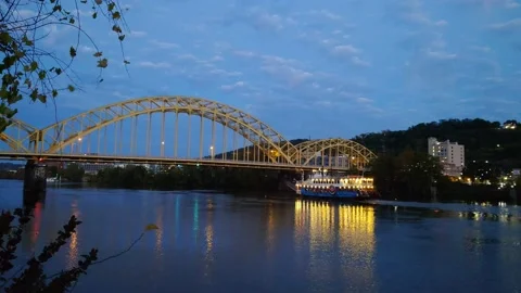 4k boat moving up river under bridge at night with lights reflecting off water Stock Footage 164056620