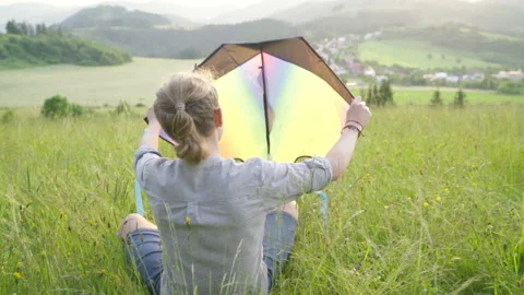 4K  boy sitting on the meadow grass and preparing colorful rainbow kite toy for  Stock-Footage 156264361