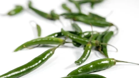 4K bright green chilli peppers focus pull against white background Video stock 88491003