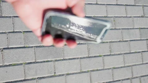 4k, broken Apple iPhone in hand on the background of the sidewalk vertical video Stock Footage 230998306