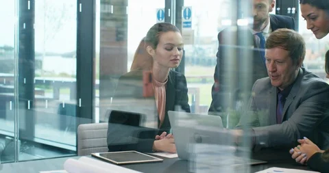4K Business execs in a meeting, looking at laptop &amp; brainstorming Stock Footage 118723192