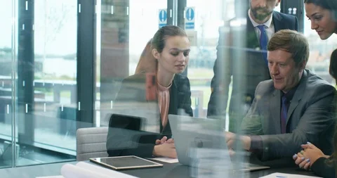 4K Business execs in a meeting, looking at laptop &amp; brainstorming Stock Footage 118915664
