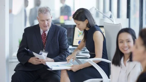 4K Business managers at a training seminar looking at paperwork &amp; discussing Stock Footage 73021679