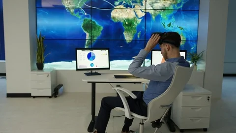 4K Businessman interacting with a virtual reality headset in futuristic office Stock Footage 75978086