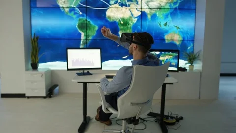 4K Businessman interacting with a virtual reality headset in futuristic office Stock Footage 75978766