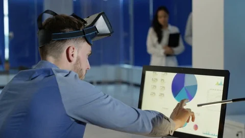 4K Businessman interacting with a virtual reality headset in futuristic office Stock Footage 75979653