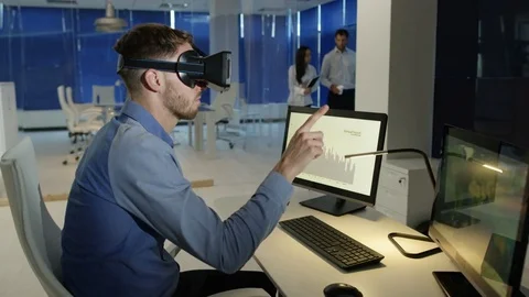 4K Businessman interacting with a virtual reality headset in futuristic office Stock Footage 75980247