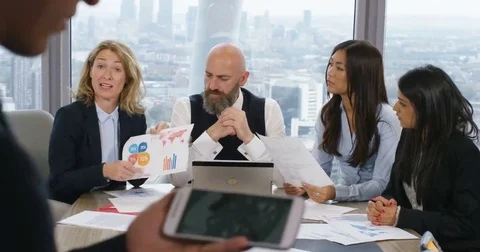 4K Businessman using smartphone with graphics to communicate ideas to colleagues Stock Footage 69143538