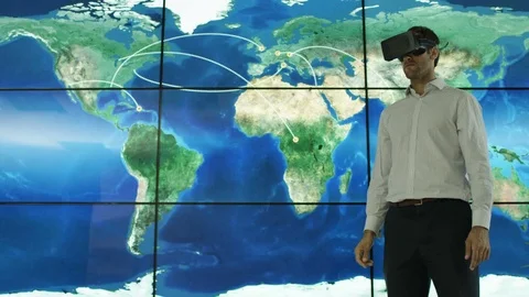 4K Businessman with a virtual reality headset in front of animated world map Stock Footage 75972079