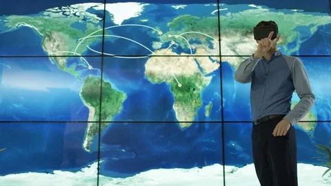 4K Businessman with a virtual reality headset in front of animated world map Stock Footage 75973985