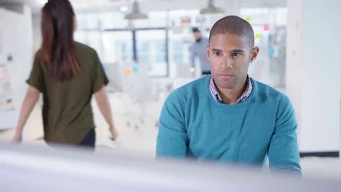 4K Businessman working on computer at his desk with colleagues in a meeting Video stock 76046727