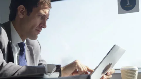 4k Businessman working on digital tablet &amp; drinking coffee on train journey Vidéo 63255740