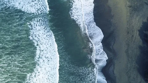 4K Camera closing in on waves rolling onto the volcanic sand beach Stock Footage 115507486