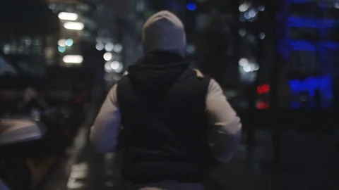 4K Camera follows a man running in the city at night, in slow motion Stock Footage 72679652
