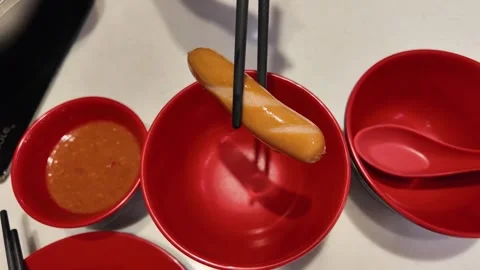 4K Camera footage Sausage held by chopsticks over red bowl Stock Footage 325649614