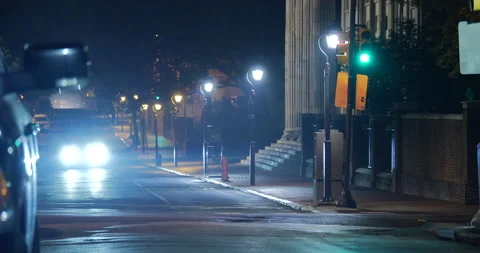 4K CAR DRIVES DOWN EMPTY CITY STREET AT NIGHT WITH HEADLIGHTS SHINING Stock Footage 131108143
