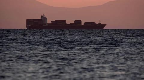 4K cargo freighter ship silhouetted on the horizon at dusk,long shot,telephoto. Stock Footage 66246290