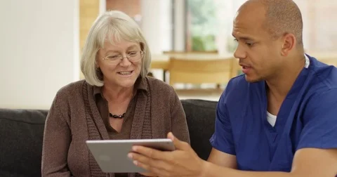 4K Caring community doctor helping senior lady to use computer tablet in her hom Stock Footage 81198731