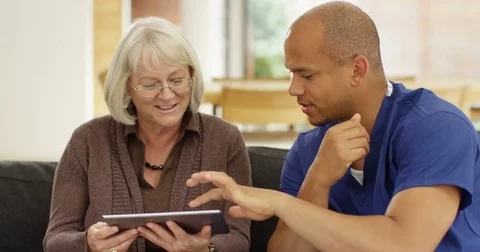 4K Caring home support worker teaching mature lady to use digital tablet at home Stock Footage 81201347
