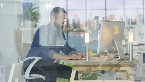 4K Casual businessman talking on phone &amp; working on computer in creative office. 스톡 동영상 69786953