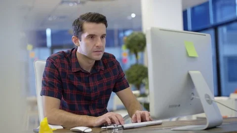 4K Casual businessman working on computer &amp; talking on phone in creative office Stock Footage 75999954
