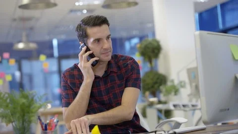 4K Casual businessman working on computer &amp; talking on phone in creative office Stock Footage 76000149