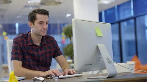 4K Casual businessman working on computer &amp; talking on phone in creative office Stock Footage 76000599