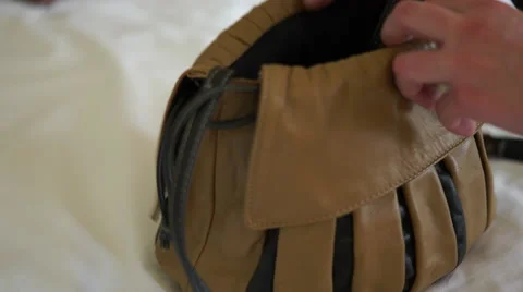 4K caucasian hands placing bits and pieces into brown and black handbag Stock Footage 63121936