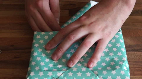 4K caucasian hands wrap starry paper around present and tape it down Stock Footage 55289063