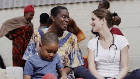 4K Charity worker talking to mother of young boy in a poor African community Stock Footage 72687408