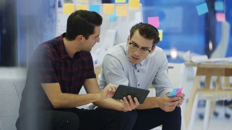 4K Cheerful casual businessmen looking at tablet computer in creative office Stock Footage