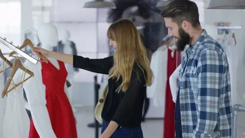 4K Cheerful couple shopping, looking at clothes in boutique clothing store Stock Footage 70683027