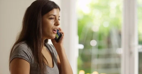 4K Cheerful Hispanic woman talking on phone at home on a bright sunny day Stock Footage