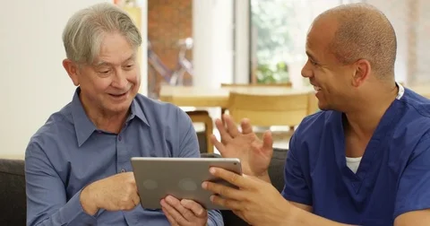 4K Cheerful home support carer teaching senior man to use computer tablet Stock Footage 81477565