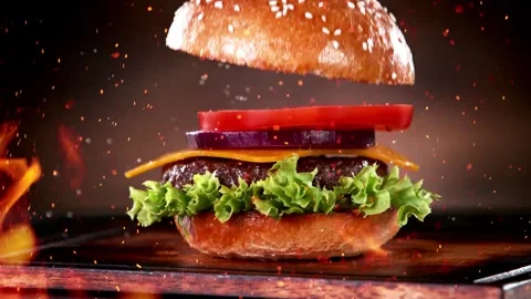 4K Cheeseburger Ingredients Falling Against Fiery Flame Background Video stock 332157752