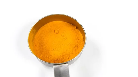 4K chef placing Yellow Turmeric spinning on white surface background in cup Stock Footage 88479585