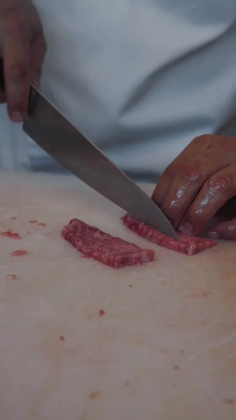 4K chef slicing wagyu beef sashimi with knife kitchen counter - vertical video Stock Footage 315123607