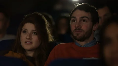 4K Cinema audience reacts to scary movie, with focus on young dating couple Stock Footage