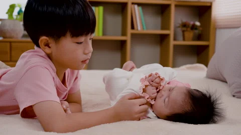 4K, Close Up Asian boy caring for his 3-month-old newborn sister in bed. Stock Footage 203894249