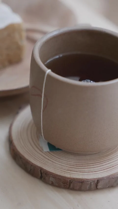 4K Close-Up Beige Ceramic Tea Cup Tea Bag String Hanging Tabletop Stock Footage 339267644