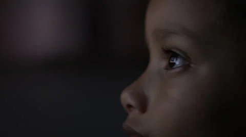 4K Close up of child's eyes watching a colourful screen in the dark Stock Footage