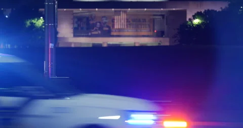 4K CLOSE UP OF COP CAR PASSING BY ILLUMINATED MUSEUM AT NIGHT Video stock 132603139
