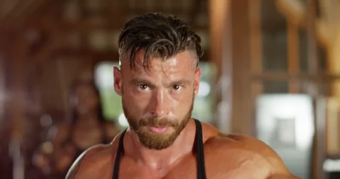 4K Close up on face with shot widening out, muscular man working out at the gym Stock Footage 94835641
