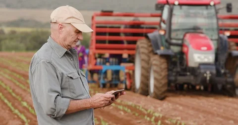 4K close-up of a farmer monitoring an automated planting machine with a tablet Stock Footage
