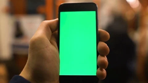 4K Close up of hand holding a smartphone with green screen display at Stock Footage 73839651