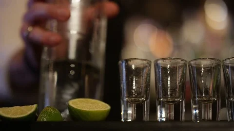 4K Close Up On Hands Of Barman Pouring Liquor Into Row Of Shot Glasses Video stock 75628447