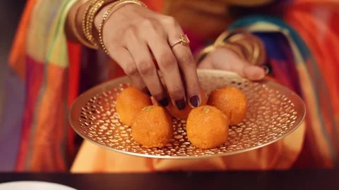 4K Close-up Lady Serving Traditional Indian Motichoor Laddu Sweet Gold Video stock 330479518